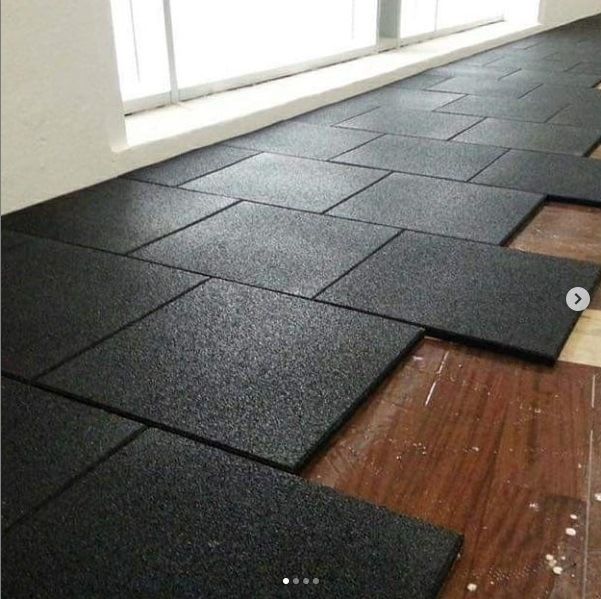 Black rubber interlocking gym flooring tiles being installed