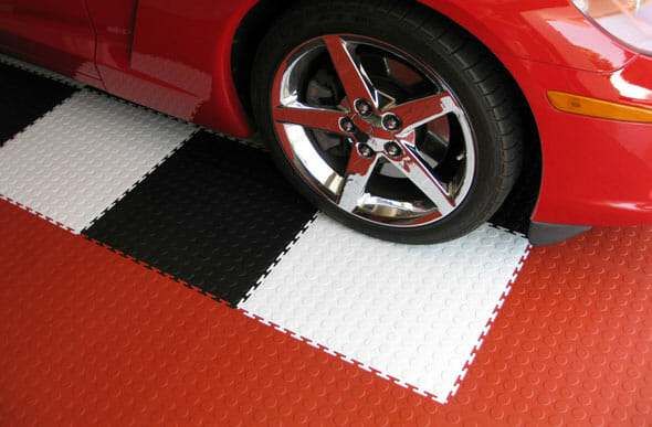 Red, black, and white interlocking garage floor tiles under sports car