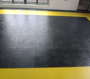 Rubber good for flooring — black interlocking tiles with yellow safety edge in a garage bay