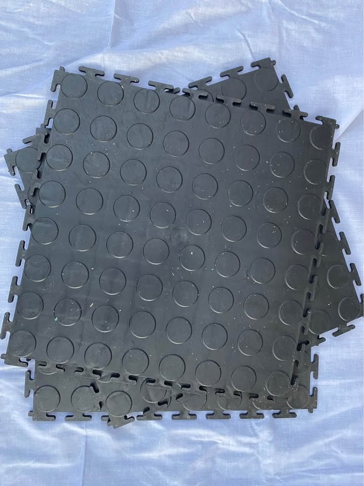 Stacked interlocking PVC floor tiles with coin surface